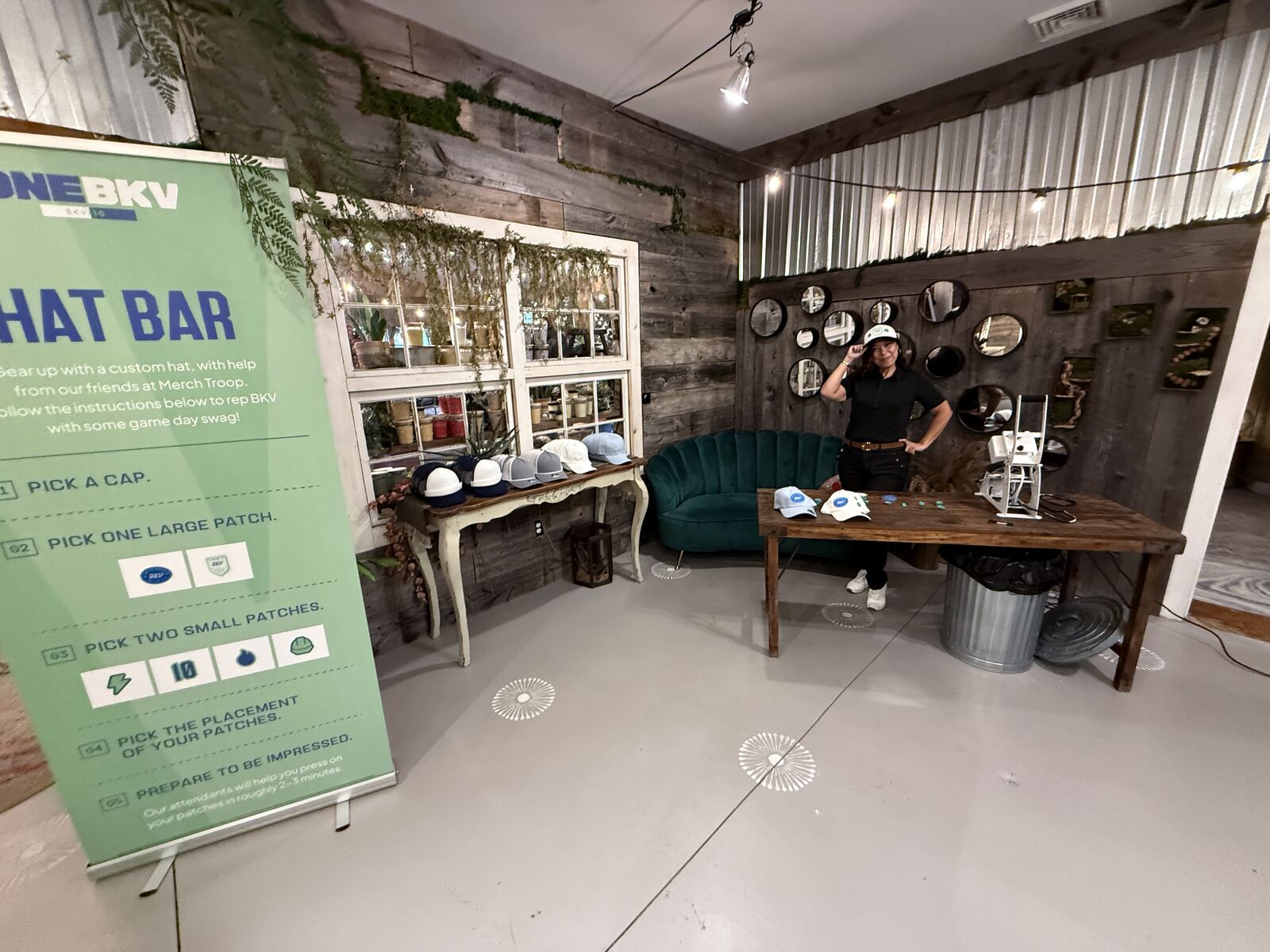 Interactive hat bar customization booth with a woman decorating hats while guests browse hat and patch options
