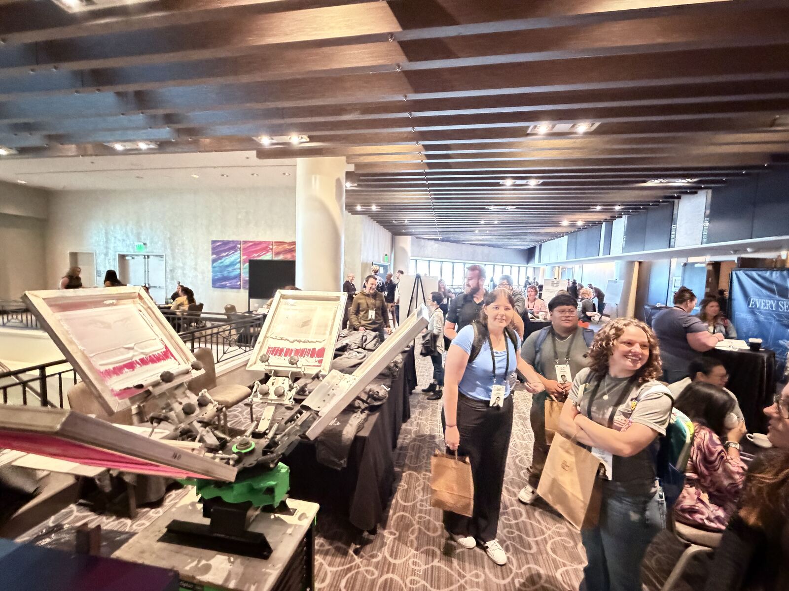 Large live-printing booth with multiple stations and guests examining finished pieces